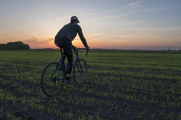 Lutsk, Ukrayna - 5 Nisan 2018: Adam bir bisiklet'nde günbatımı bir sahaya sürmek.