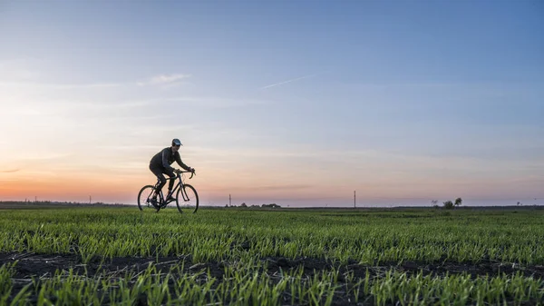 Lutsk, Ucrânia - 5 de abril de 2018: Homem anda de bicicleta ao pôr-do-sol em um campo . — Fotografia de Stock