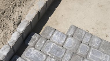 Dikkatli bir şekilde yerleştirerek bir pozisyonda düzeltilmiş ve komisyonlu topraklarında temel yeni dış parke taşı döşeme montaj işlemi. Kum Vakfı. Bina.