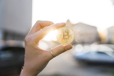 Altın bitcoin para el üzerinde günbatımı arka plan bulanık. Bir kripto para birimi sanal para tutan el. İş, ticaret, Döviz, dijital para.