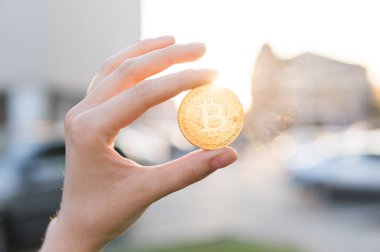 Altın bitcoin para el üzerinde günbatımı arka plan bulanık. Bir kripto para birimi sanal para tutan el. İş, ticaret, Döviz, dijital para.