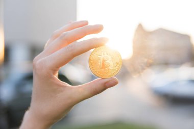Altın bitcoin para el üzerinde günbatımı arka plan bulanık. Bir kripto para birimi sanal para tutan el. İş, ticaret, Döviz, dijital para.