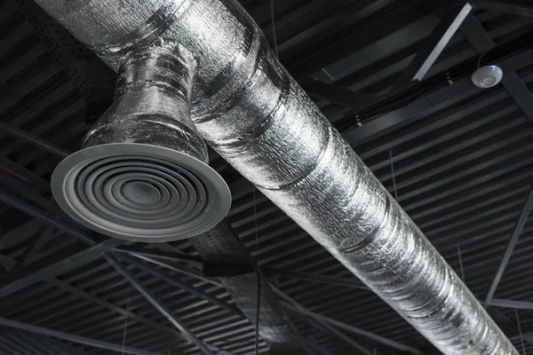 Sistema di ventilazione sul soffitto di grandi edifici. Tubi di ventilazione in materiale isolante argentato appesi al soffitto all'interno di un nuovo edificio . — Foto Stock