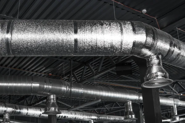 Ventilation system on the ceiling of large buildings. Ventilation pipes in silver insulation material hanging from the ceiling inside new building. — Stock Photo, Image