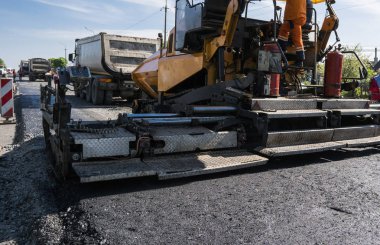 Asfalt Finişer makine yol yapımı sırasında işletim ve tamir işçi çalışıyor. Bir fayans ustası son işlemci, asfalt tamamlayıcı veya kaldırım makine asfalt tabakası yerleştirerek. Asfaltlanması