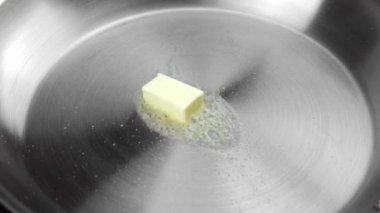 Bir sıcak metal kızartma tavada tereyağı erime.