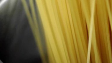 Beyaz bir arka plan üzerinde çelik bir tavada spagetti aşağı bir aşçı koyar.