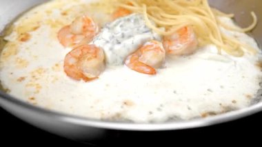 Çelik tavada spagetti sosu ve karides ile karıştırma.