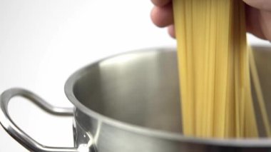 Beyaz bir arka plan üzerinde çelik bir tavada spagetti aşağı bir aşçı koyar.