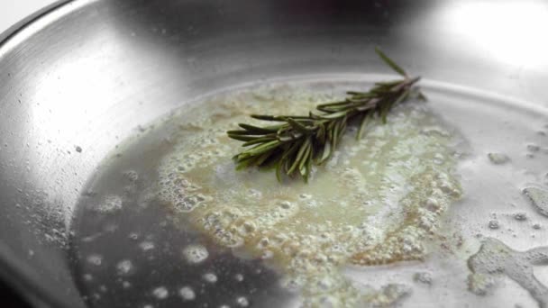 Romarin et ail tombent sur le beurre fondu dans une poêle à frire en métal chaud . — Video