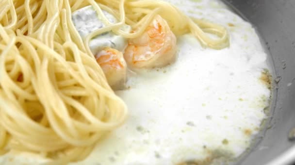 Agitar espaguetis con salsa y camarones en una sartén de acero . — Vídeo de stock