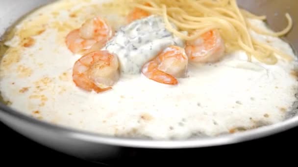 Za stálého míchání špagety s omáčkou a krevety v ocelové pánve. — Stock video