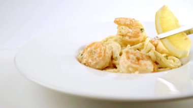 Bir karides beyaz tabakta bir limon ile dekorasyon ile pişmiş spagetti makarna.