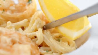 Bir karides beyaz tabakta bir limon ile dekorasyon ile pişmiş spagetti makarna.