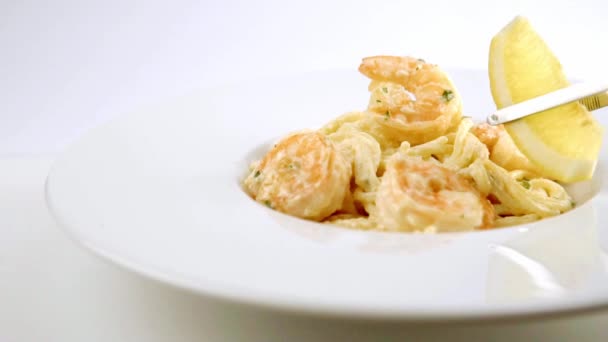 Les pâtes spaghetti cuites avec une crevette sur une assiette blanche décorée d'un citron . — Video