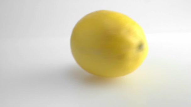 Gros plan d'un citron frais mûr filant sur la table sur fond blanc . — Video