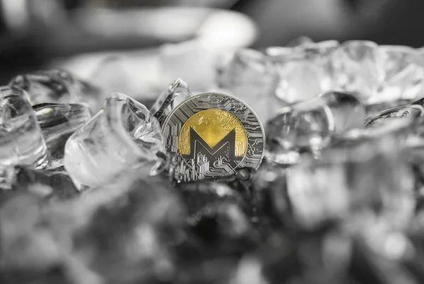 Digital currency physical metal gold monero coin on ice background. The concept of the exchange in winter. Freeze. Blockchain mining. Digital money and virtual cryptocurrency concept.