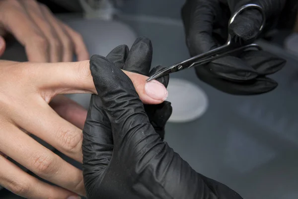 Отрезать ногти кутикулы ножницами для ногтей в профессиональном маникюрном салоне. Красивые женские ногти и маникюр . — стоковое фото