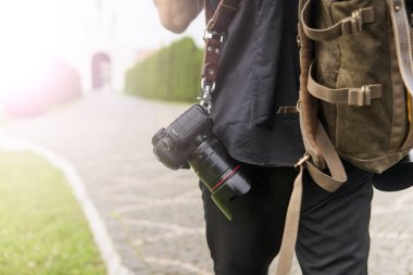 Profesyonel düğün fotoğrafçısı siyah gömlek ve iki kamera arkasında bir bir omuz askıları ve yeşil bahçesinde boş yol karşı kahverengi çanta. Düğün fotoğrafçılığı.