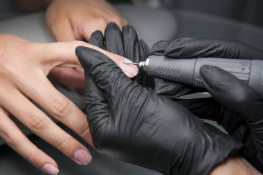 Profesyonel donanım Pedikür elektrik makine kullanarak. Öğütülmüş manikürcü kız tırnak salonu içinde çivi ve şimdi onları bir form verir. . Hastanın tıbbi pedikür usulü hakkında.