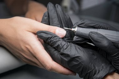 Profesyonel donanım Pedikür elektrik makine kullanarak. Öğütülmüş manikürcü kız tırnak salonu içinde çivi ve şimdi onları bir form verir. . Hastanın tıbbi pedikür usulü hakkında.