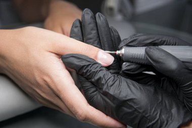 Profesyonel donanım Pedikür elektrik makine kullanarak. Öğütülmüş manikürcü kız tırnak salonu içinde çivi ve şimdi onları bir form verir. . Hastanın tıbbi pedikür usulü hakkında.