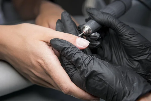 Professionele hardware pedicure met behulp van elektrische machine. De manicure gemalen de nagels van het meisje in de nagel salon en nu geeft hen een vorm. . Patiënt op medische pedicure procedure. — Stockfoto