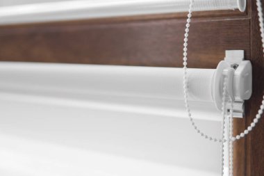 Oturma odasındaki ahşap desenli plastik camdaki beyaz kumaş silindirlerin ayrıntıları..