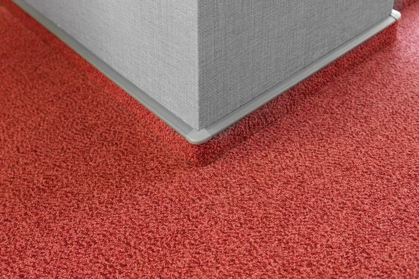 Carpet floor with a carpet baseboard on a grey wall.