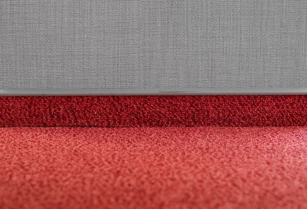 Suelo de alfombra con un zócalo de alfombra en una pared gris . — Foto de Stock