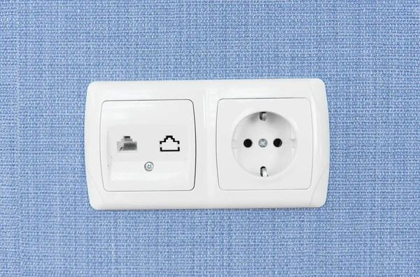 Socket on a blue wall, a multifunction outlet with an internet connection and european-style outlets