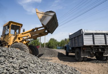 Sarı yükleyici kamyon içine taş stabilize yol inşaat çalışmaları sırasında teslim. Yolun taşları. Boşaltma taş.