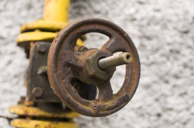 Eski gaz vinç ve boru arka plan gri bir duvar üzerinde yıpranmış. Eski gaz kapı sarı renkteki bir boru ve boru engeller. Boru hattı ile duvara vererek gaz için Vinçler.