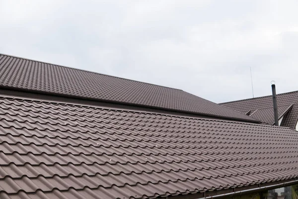 Techo moderno cubierto con láminas de techo de metal marrón recubierto de PVC efecto azulejo contra el cielo nublado . —  Fotos de Stock