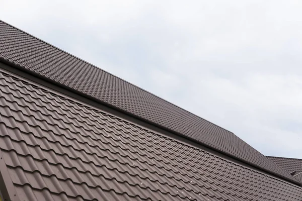 Techo moderno cubierto con láminas de techo de metal marrón recubierto de PVC efecto azulejo contra el cielo nublado . —  Fotos de Stock