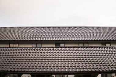 Modern çatı kiremit etkisi ile Pvc kaplı kahverengi metal çatı sayfaları bulutlu gökyüzü karşı kaplı..