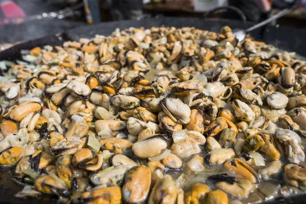 Fresh mussels at grill pan. Seafood barbecue outdoors. Picnic healthy food, mussels without a shells. Seafood, grilled appetizing mussels on a black plate. — Stock Photo, Image