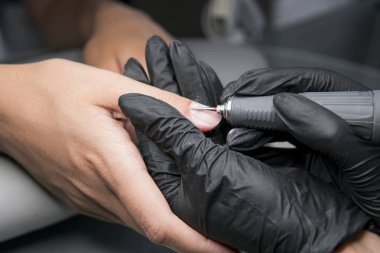 Profesyonel donanım Pedikür elektrik makine kullanarak. Öğütülmüş manikürcü kız tırnak salonu içinde çivi ve şimdi onları bir form verir. . Hastanın tıbbi pedikür usulü hakkında.