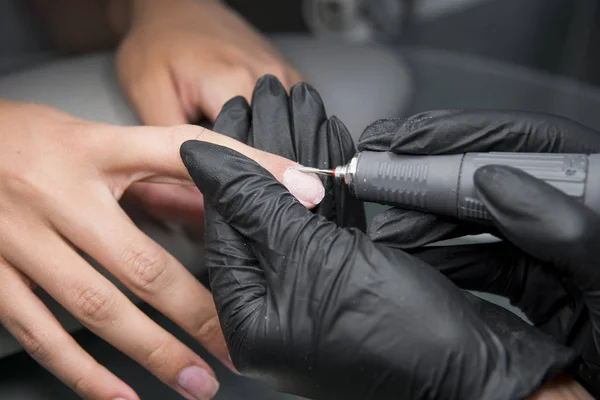 Professionele hardware pedicure met behulp van elektrische machine. De manicure gemalen de nagels van het meisje in de nagel salon en nu geeft hen een vorm. . Patiënt op medische pedicure procedure. — Stockfoto