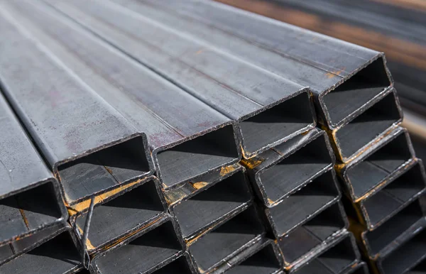 Square flat-rolled pipe metal profile in packs at the warehouse of metal products. Weathered metals profiles for construction. Metal corrosion. — Stock Photo, Image