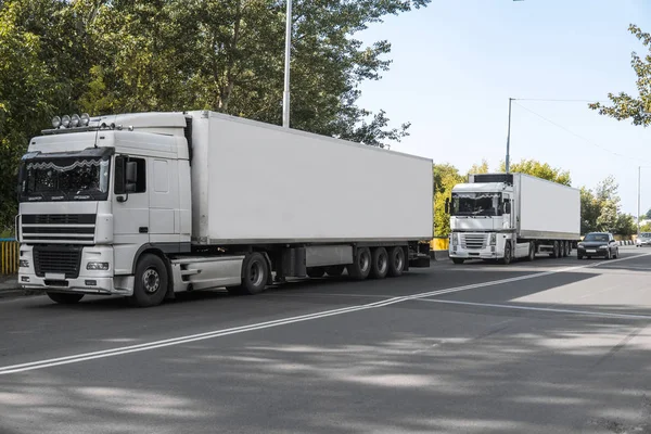 Two trucks on a road against blue sky and trees, cargo transportation concept. — Stock Photo, Image