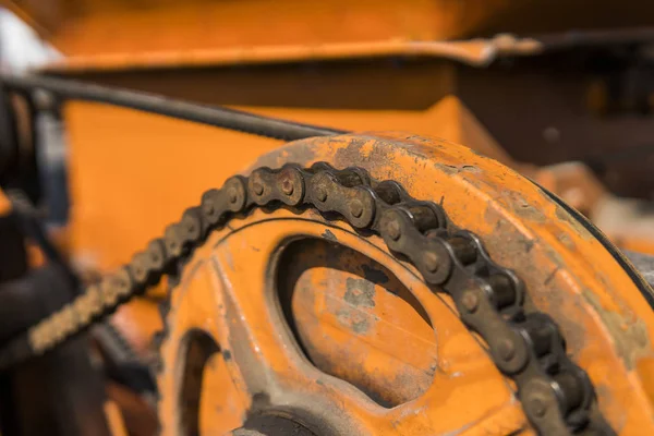 The mechanism of the chain transmission on a orange tracktor. — Stock Photo, Image