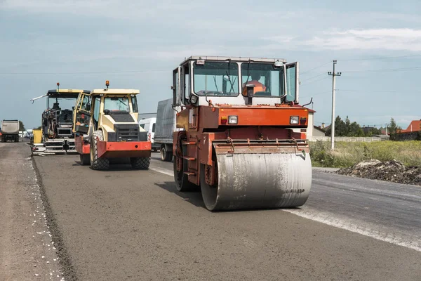 Orange Heavy Vibration roller compactor at asphalt pavement works for road repairing. Working on the new road construction site. Repairing. — Stock Photo, Image