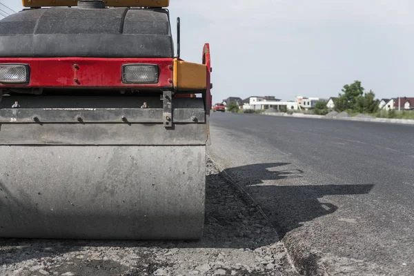 Orange drgania rolki kompaktor stojący na ziemi w pobliżu asfalty drogowe w budownictwie drogowym i naprawa nawierzchni asfaltowej działa z błękitnego nieba. — Zdjęcie stockowe