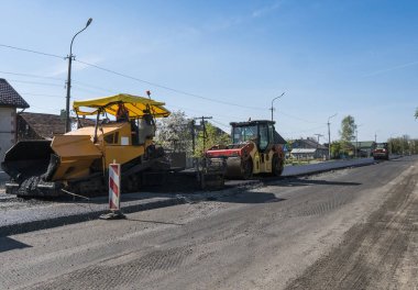 Asfalt Finişer makine yol yapımı sırasında işletim ve tamir işçi çalışıyor. Bir fayans ustası son işlemci, asfalt tamamlayıcı veya kaldırım makine asfalt tabakası yerleştirerek. Asfaltlanması