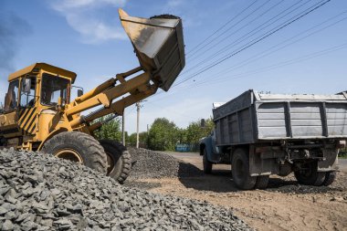 Sarı yükleyici kamyon içine taş stabilize yol inşaat çalışmaları sırasında teslim. Yolun taşları. Boşaltma taş.