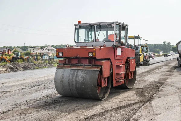 Orange Heavy Vibration roller compactor at asphalt pavement works for road repairing. Working on the new road construction site. Repairing.