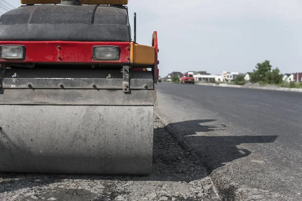 Orange drgania rolki kompaktor stojący na ziemi w pobliżu asfalty drogowe w budownictwie drogowym i naprawa nawierzchni asfaltowej działa z błękitnego nieba. — Zdjęcie stockowe