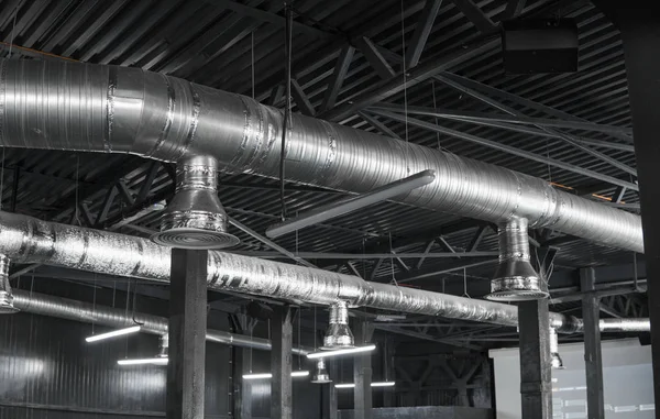 Sistema de ventilação no teto de grandes edifícios. Tubos de ventilação em material de isolamento de prata pendurado no teto dentro do novo edifício . — Fotografia de Stock