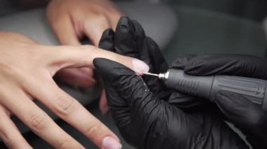 Profesyonel donanım Pedikür elektrik makine kullanarak. Öğütülmüş manikürcü kız tırnak salonu içinde çivi ve şimdi onları bir form verir. Hastanın tıbbi pedikür usulü hakkında.